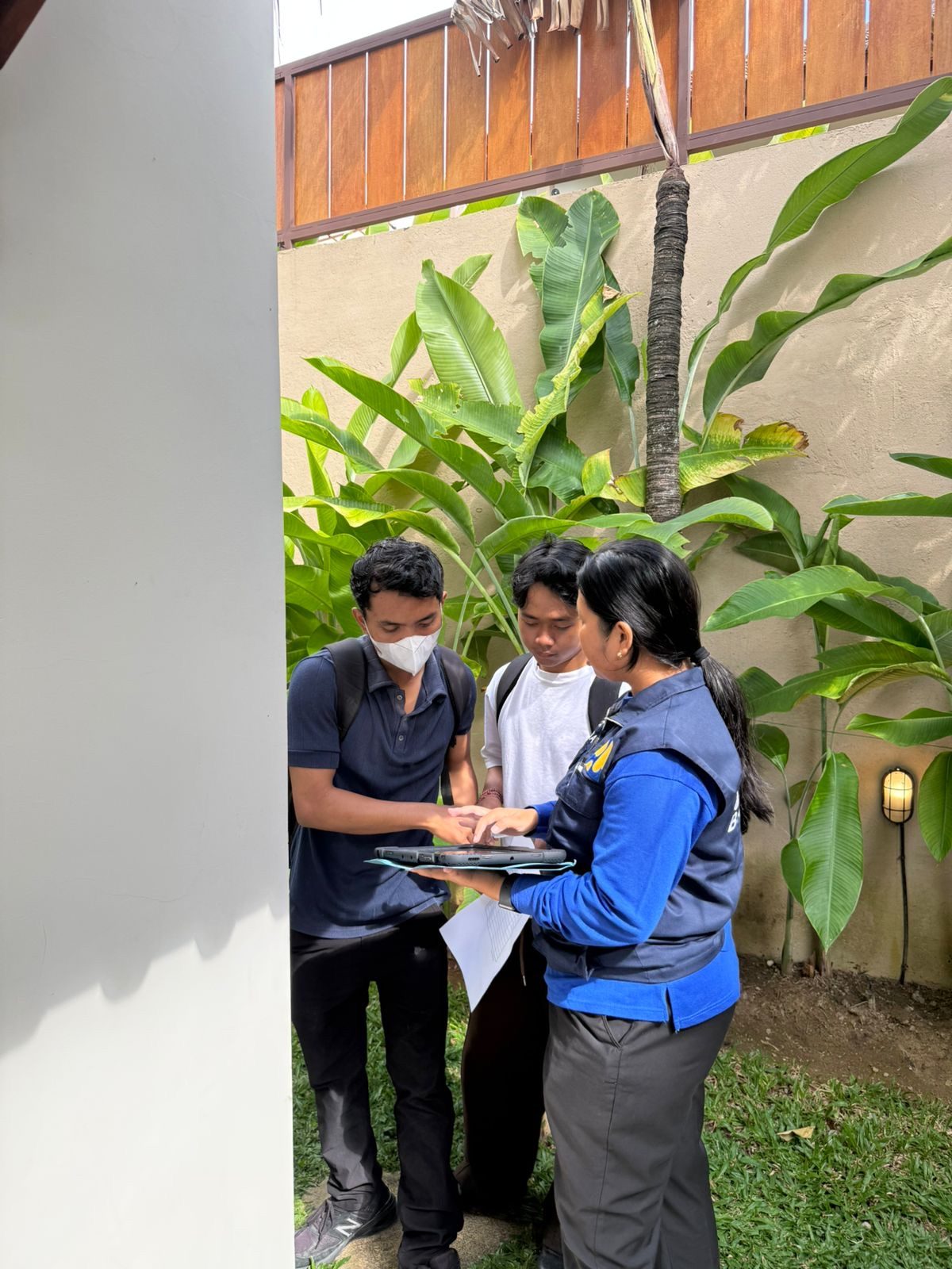 Petugas SIMBG Badung memverifikasi data pengukuran bangunan di layar tablet rugged, didampingi dua surveyor JKK