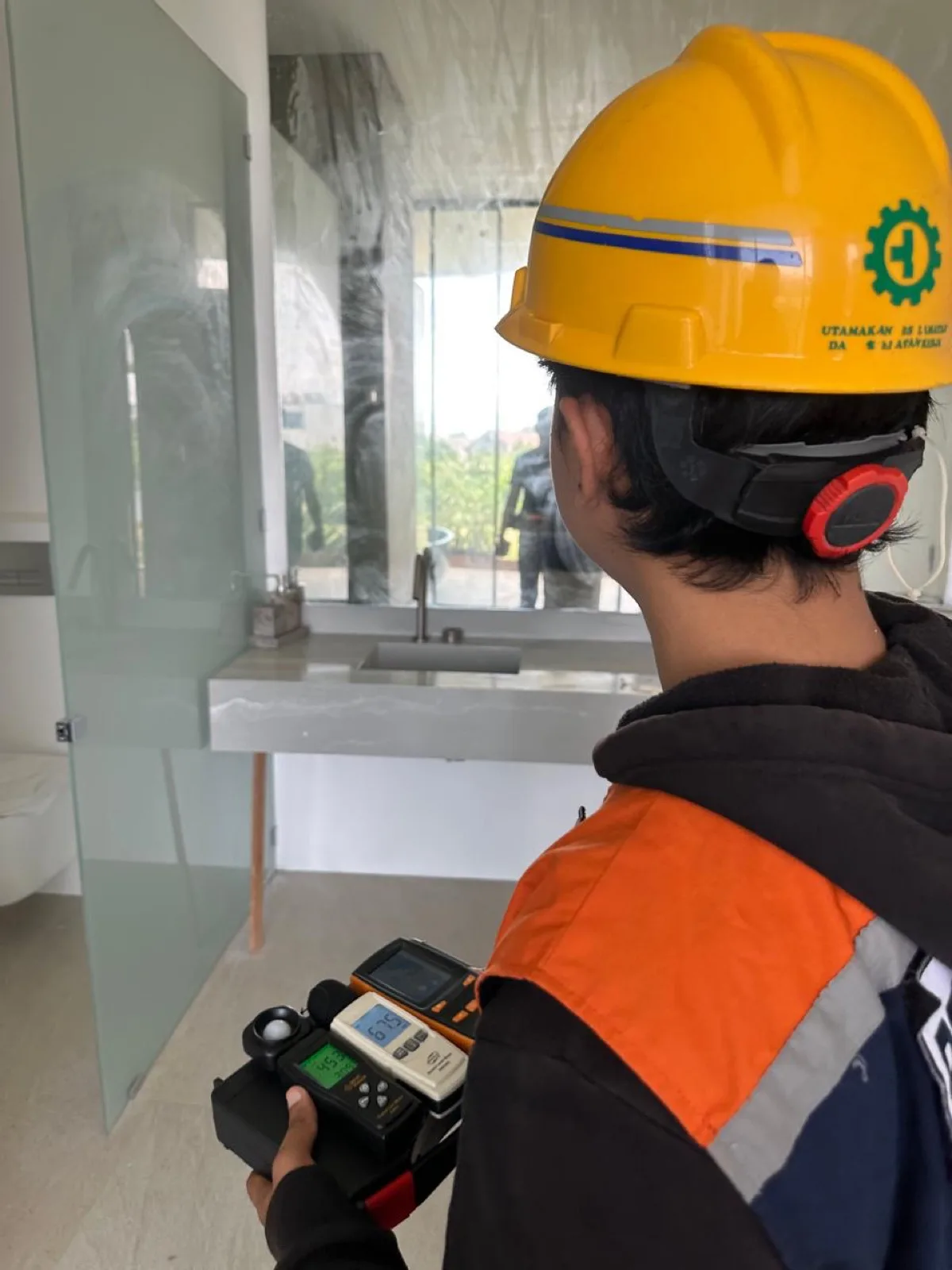 JKK surveyor inspecting a building with measuring instruments during a technical function compliance assessment in Badung